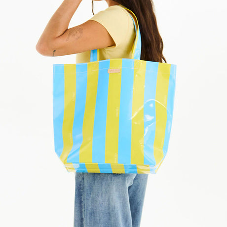 Person holding a blue and yellow striped tote bag on a white background