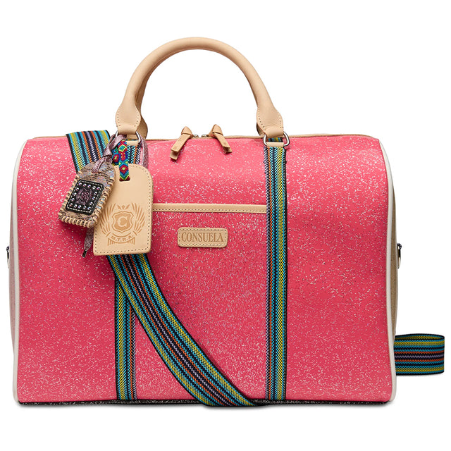 A structured pink jet setter bag with beige leather handles and trim, featuring a colorful woven strap and a silver metal clasp, shown against a plain white background.