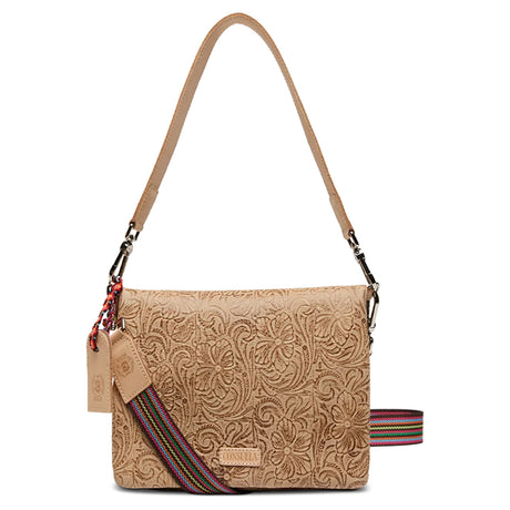A tan tooled leather crossbody with floral embossed patterns, featuring multiple zippered compartments, a card slot with a blue denim insert, and a yellow ID window.