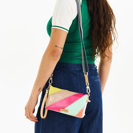 Person wearing a colorful geometric-patterned crossbody bag on a white background