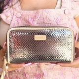 Silver patterned handbag held by a person wearing a pink floral dress.