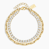 A gold-toned layered chain bracelet with clear cubic zirconia stones, shown on a light gray background. The brand name 'LUXORING' is engraved on a small tag attached to the clasp.