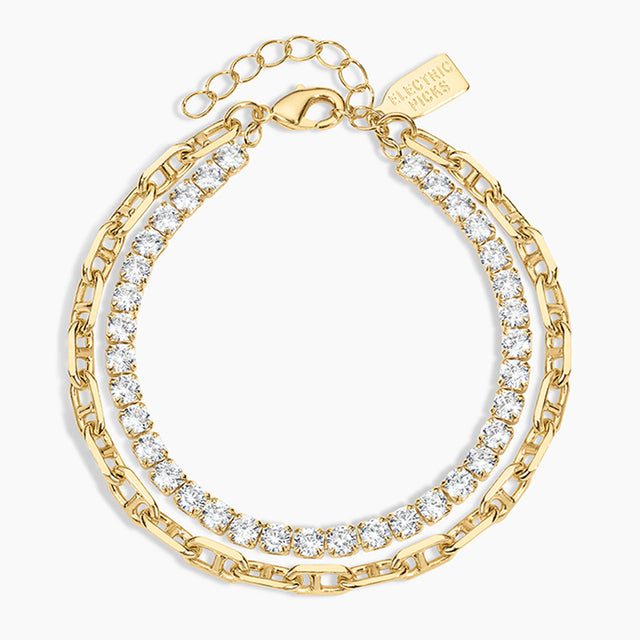 A gold-toned layered chain bracelet with clear cubic zirconia stones, shown on a light gray background. The brand name 'LUXORING' is engraved on a small tag attached to the clasp.