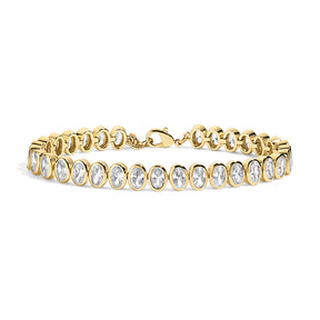 A yellow gold tennis bracelet featuring a row of bezel-set oval clear gemstones, displayed on a clean white background.