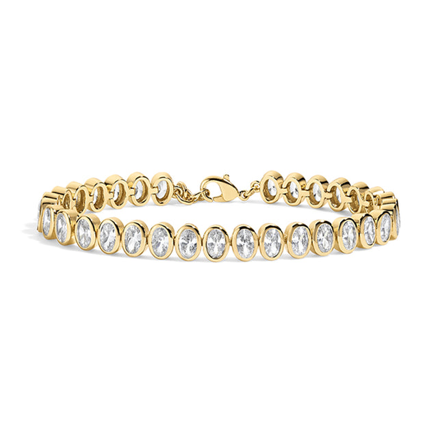 A yellow gold tennis bracelet featuring a row of bezel-set oval clear gemstones, displayed on a clean white background.