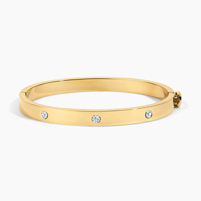 A polished yellow gold bangle bracelet with three small round clear gemstones spaced along the front, shown on a clean white background.
