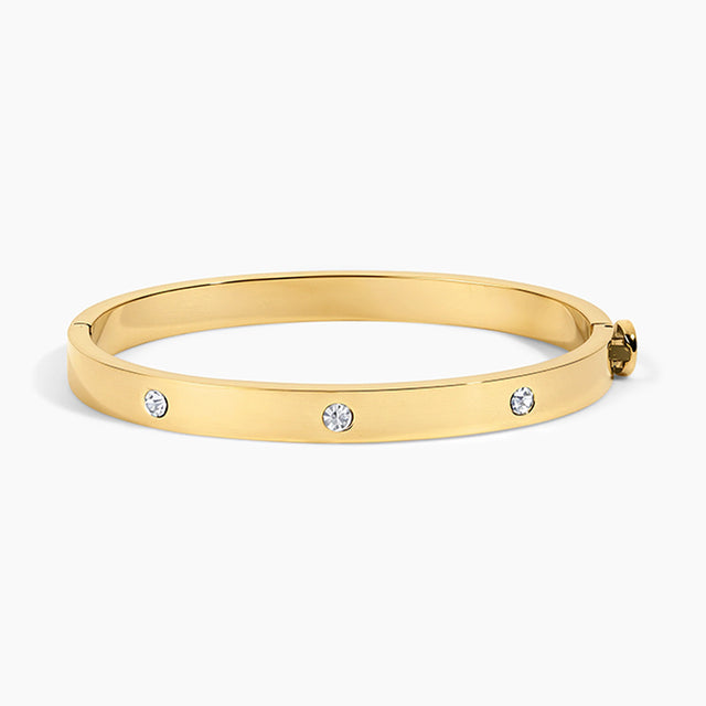 A polished yellow gold bangle bracelet with three small round clear gemstones spaced along the front, shown on a clean white background.