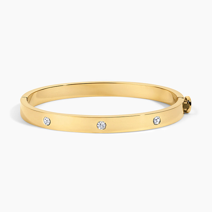 A polished yellow gold bangle bracelet with three small round clear gemstones spaced along the front, shown on a clean white background.