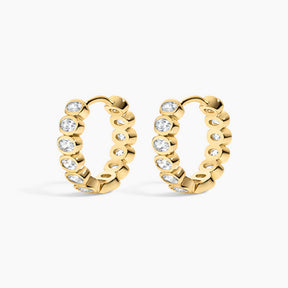 Gold hoop earrings with embedded diamonds on a white background