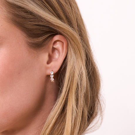 Close-up of a woman wearing a small earring with a plain background