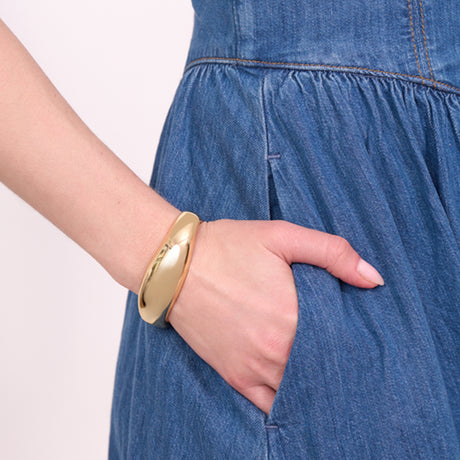 Gold bracelet on a wrist with a blue denim dress
