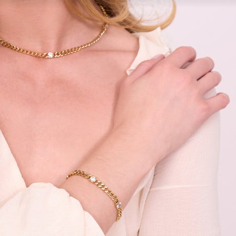 Gold chain bracelet on a person's wrist with a neutral background