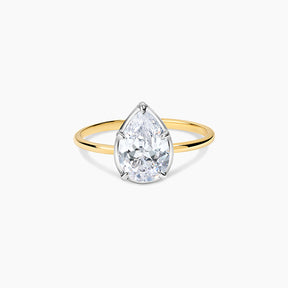 A pear-cut diamond ring with a yellow gold band and a silver-colored prong setting, shown on a clean white background.
