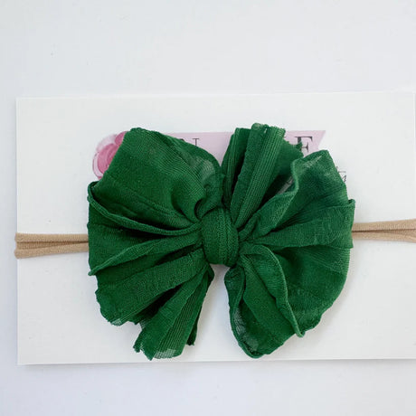 Green headband with a large bow on a white background