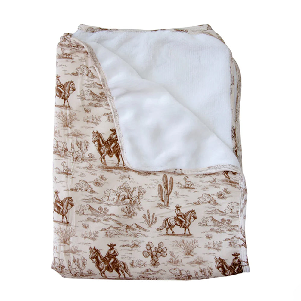 Folded blanket with cowboy and horse pattern on beige background
