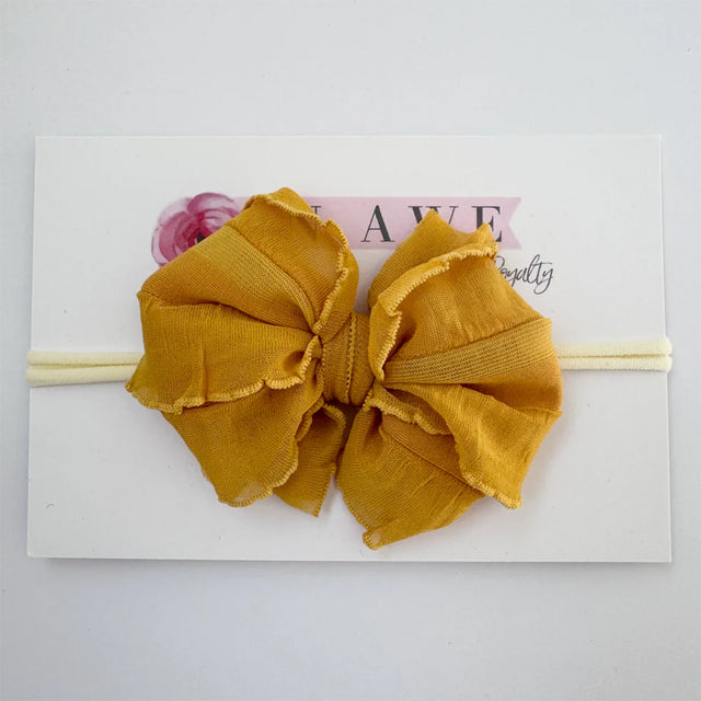 Mustard yellow headband with large bow on a white background