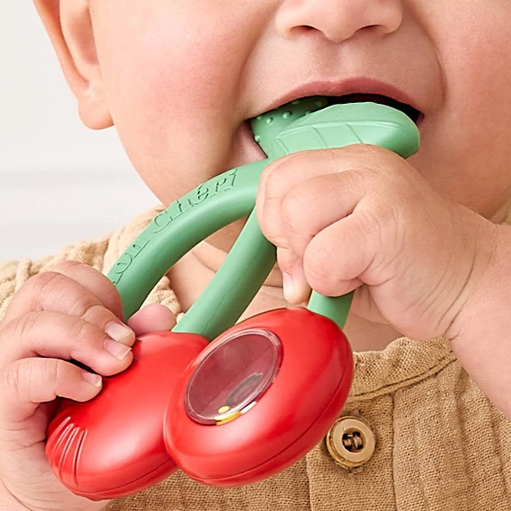 Baby holding a red and green teething toy