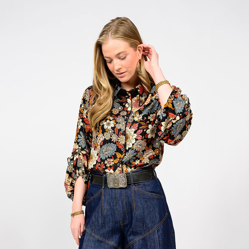 Woman wearing a floral blouse and blue jeans on a white background