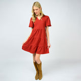 Woman wearing a red dress with tiered skirt and brown boots on a white background