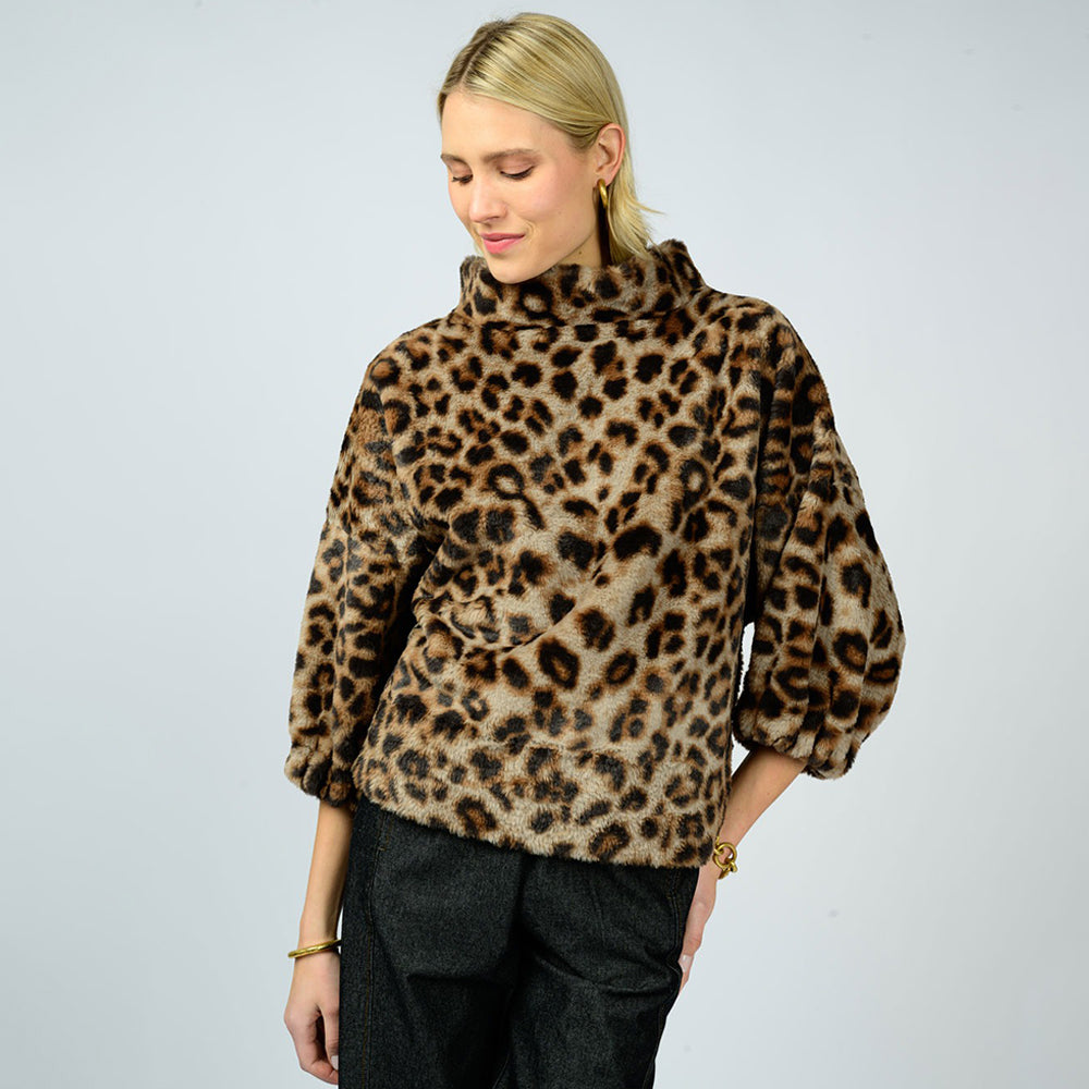 Woman wearing a leopard print sweater against a plain background