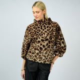 Woman wearing a leopard print sweater against a plain background