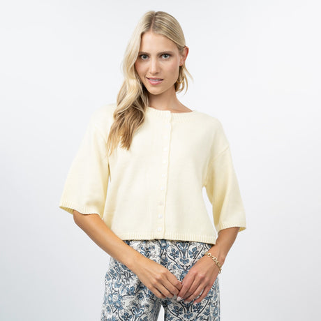 Woman wearing a light yellow top and patterned pants on a white background