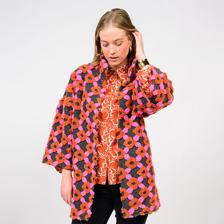 Woman wearing a colorful floral patterned coat on a white background