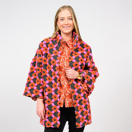 Woman wearing a colorful floral patterned coat on a white background