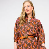 Woman wearing a brown dress with floral and horse pattern on a white background