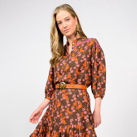 Woman wearing a patterned dress with long sleeves on a plain background
