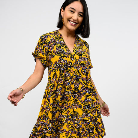 Woman wearing a yellow floral dress on a white background