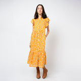 Woman wearing a yellow floral dress against a white background
