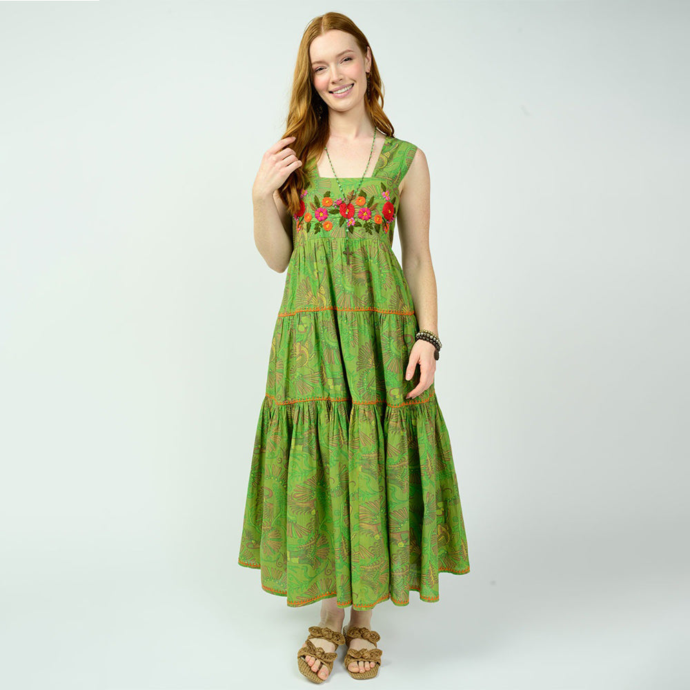 Woman wearing a green dress with floral embroidery on a white background