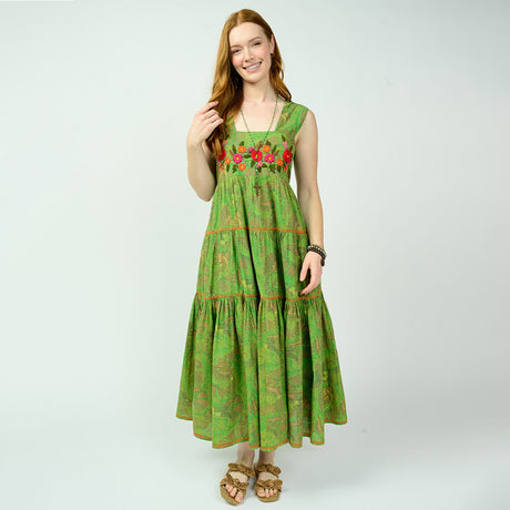 Woman wearing a green dress with floral embroidery on a white background
