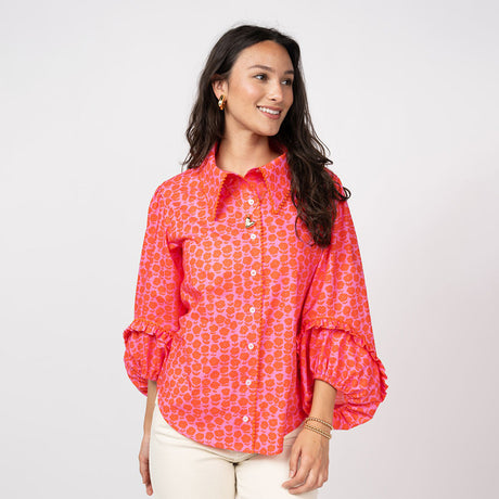 Woman wearing a bright pink patterned blouse on a white background