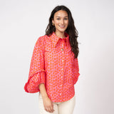 Woman wearing a bright pink patterned blouse on a white background