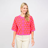 Woman wearing a pink blouse with orange heart pattern on a white background