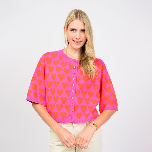 Woman wearing a pink cardigan with heart pattern on a white background