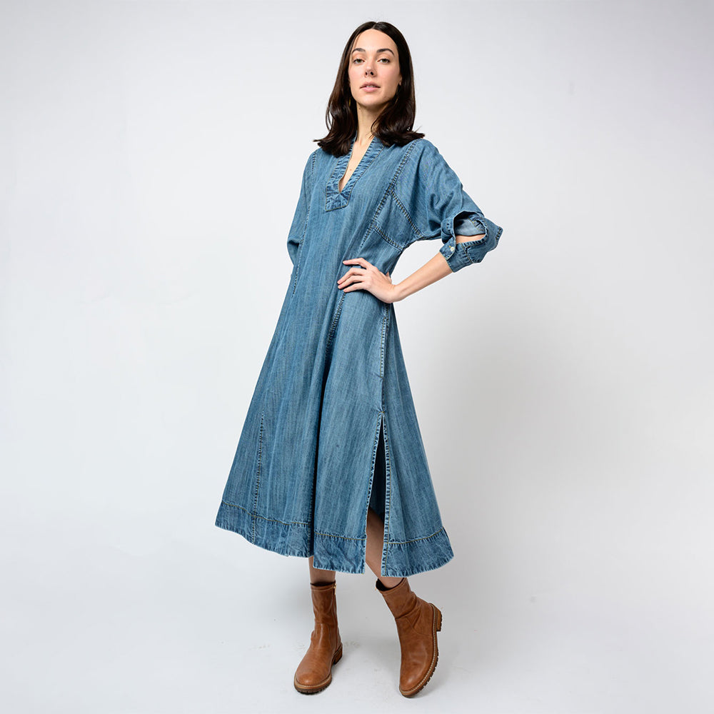 Woman wearing a blue denim dress with brown boots on a white background