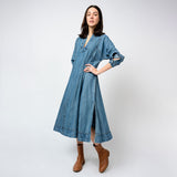 Woman wearing a blue denim dress with brown boots on a white background