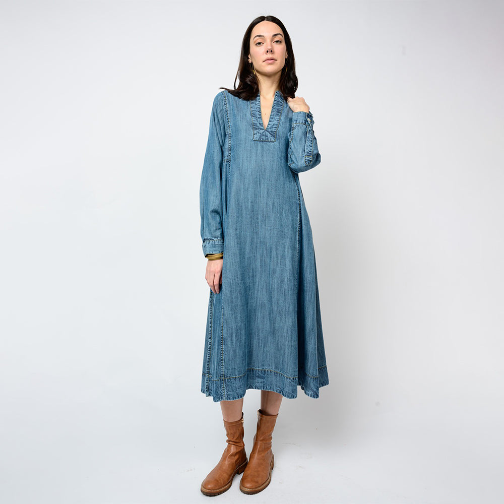 Woman wearing a blue denim dress with long sleeves on a white background