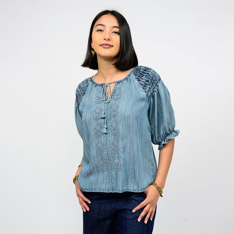 Woman wearing a blue embroidered blouse against a white background