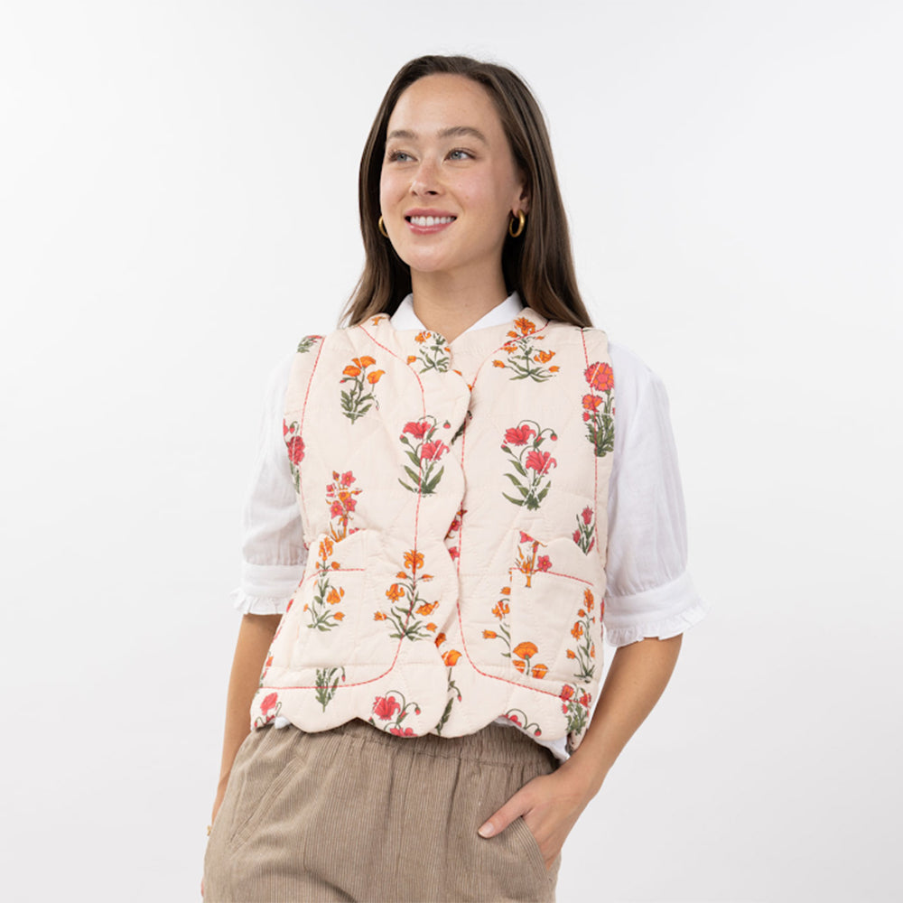 Woman wearing a floral embroidered vest over a white shirt on a white background