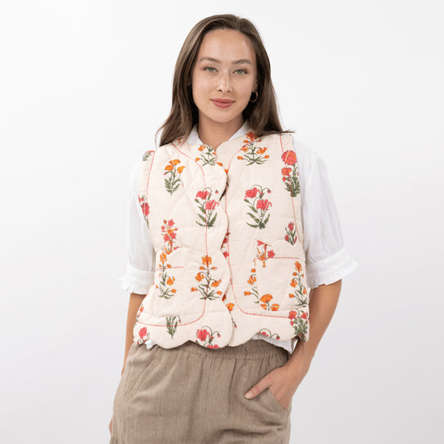 Woman wearing a floral vest over a white shirt on a white background