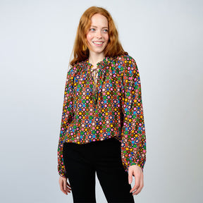 Woman wearing a colorful patterned blouse against a plain background
