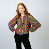 Woman wearing a colorful patterned blouse against a plain background