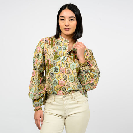 Woman wearing a patterned blouse and white pants on a white background