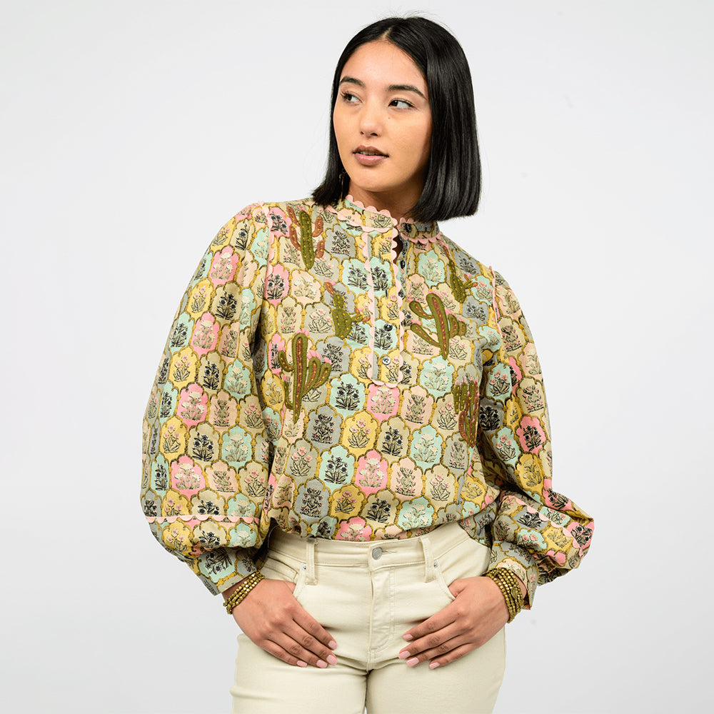 Woman wearing a patterned blouse and white pants on a white background