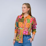 Woman wearing a colorful patchwork shirt with a plain background