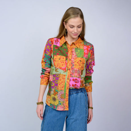 Woman wearing a colorful patchwork shirt with a plain background